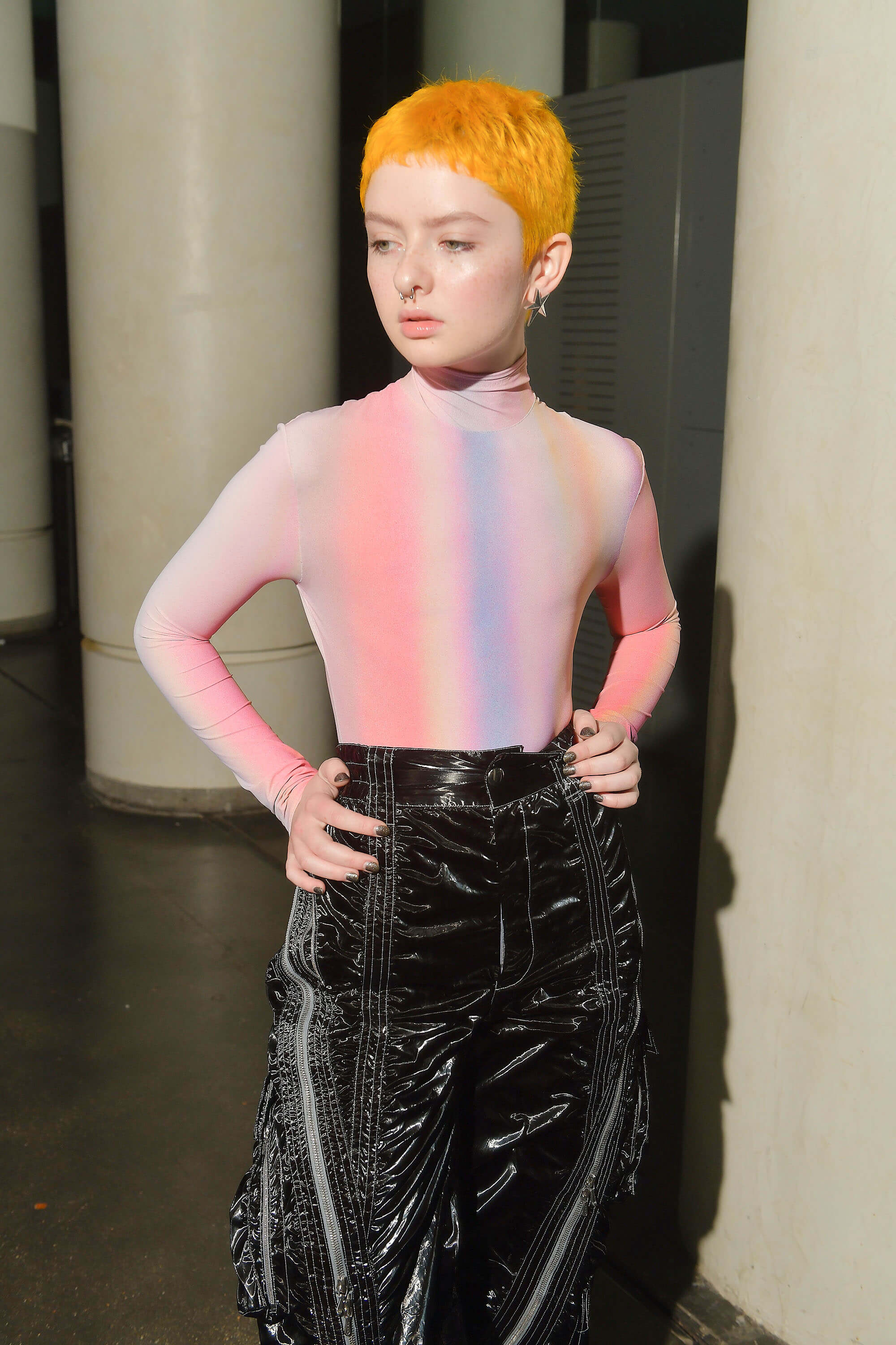 Model with short orange hair, rainbow top and black pants for Mugler