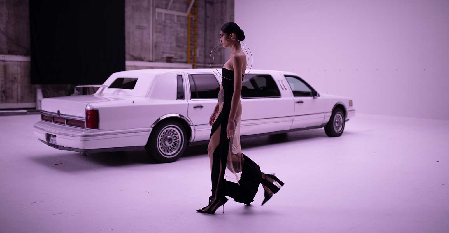 Model walking towards white stretch limo for Mugler
