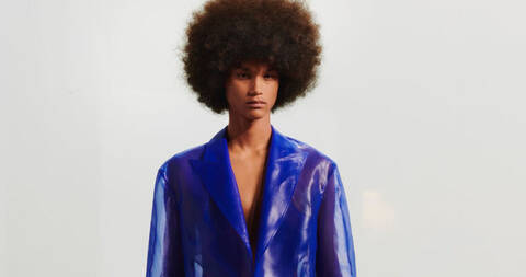 Model with afro hairstyle in blue patent blazer