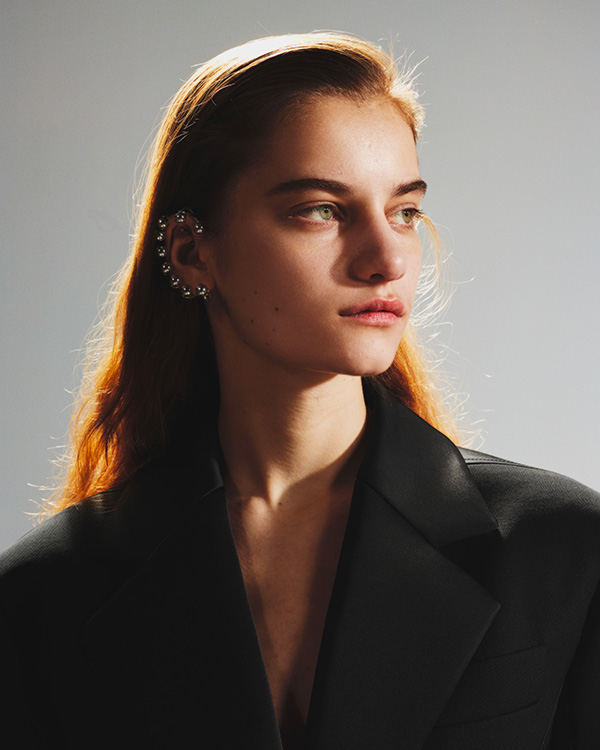 Model in black blazer with earrings surrounding ears