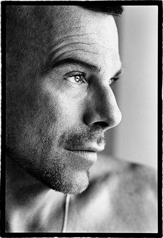 A black and white photo of a close up of a man with beard stubble 